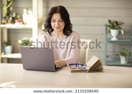 Woman 35-40 years old, works in a laptop at home, online work. High quality photo Royalty-Free Stock Photo #2110108640