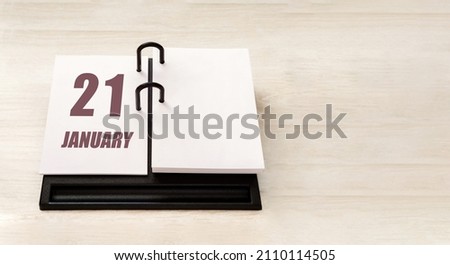 january 21. 21th day of month, calendar date. Stand for desktop calendar on beige wooden background. Concept of day of year, time planner, winter month.