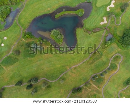 Shooting from the air. Green meadow, lake and paths. Rural scene, pasture, beautiful nature. Agriculture, calm scenes, ecology, geology, geography, nature, map, planning.