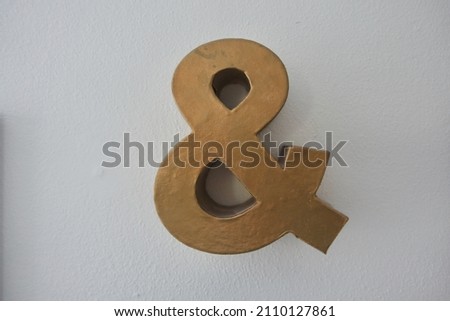 Gold 3D Ampersand on Gray Wall