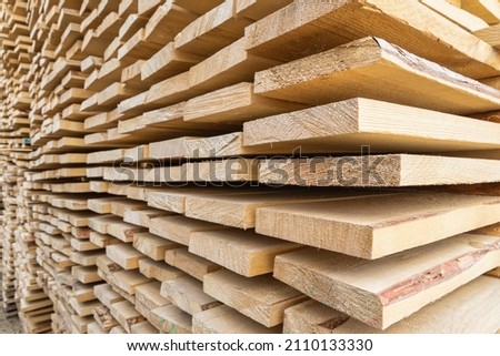 Perspective angle of wooden planks in close-up at a lumber warehouse. Background of boards. Royalty-Free Stock Photo #2110133330