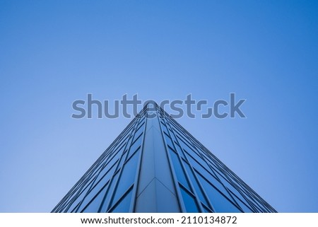 Low angle view of glass facade of tall office building against clear blue sky Royalty-Free Stock Photo #2110134872