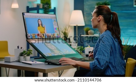 Professional artist editing pictures using retoucher on touch screen monitor. Woman photographer retouching photos with edit software and graphic tablet while holding stylus. Image editor