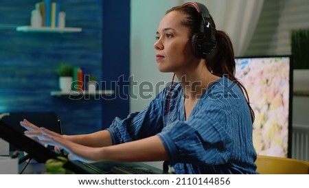 Editor wearing headphones and retouching pictures with editing app on touch screen monitor at photography studio. Woman photographer working on image design for media production.