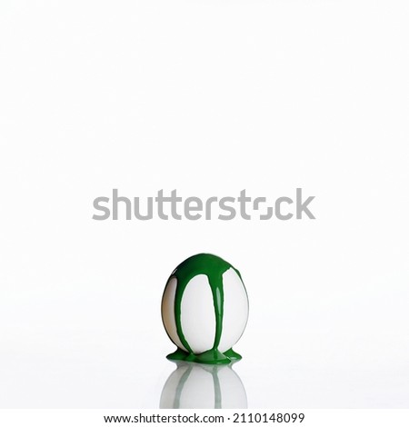 Easter egg isolated on a white background. Green paint runs down the egg. minimalist poster