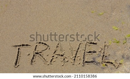 Travel concept - inscription in the sand. Sandy coast of the sea. Motivation. Ocean wave. The word travel is written on the sea beach. Vacations on the shore.