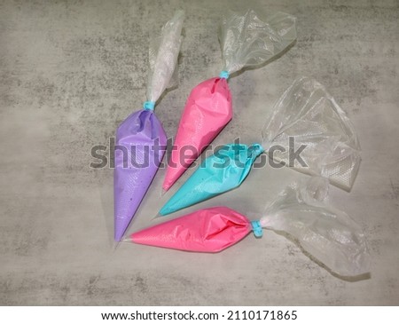 purple, pink and aqua color royal icing  in piping bags for decorating ocean and mermaid theme sugar cookies.