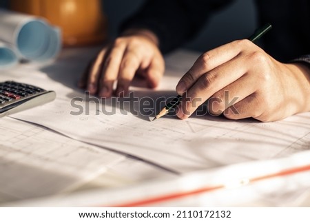 Designer are working on new project blueprint Design at desk in office. Architects workplace - architectural project and hand with pencil. Architectural plans. Blue print is fake only for stock photo.
