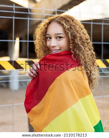pretty hispanic woman with curly hair, with rainbow flag gay pride, lgbt