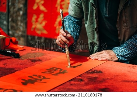 People write Spring Festival couplets with brushes with gold lacquer to celebrate Chinese New Year. Chinese characters"yi" "fu"mean good fortune. Royalty-Free Stock Photo #2110180178