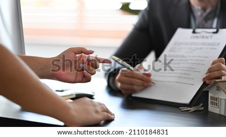 Financial advisor consulting  with clients about new house and showing contract document.