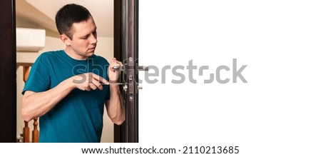 a man repairing a door knob. locksmith fixing a wooden door. banner