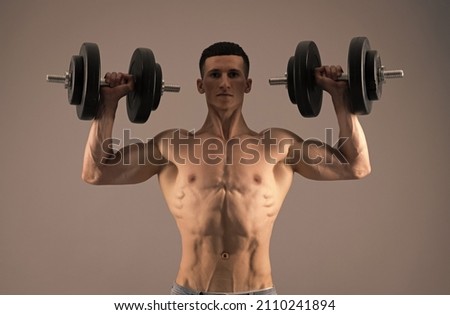 Strongman with muscular torso lift dumbbells in strong arms biceps triceps grey background, strength Royalty-Free Stock Photo #2110241894