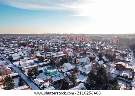 Aerial photography concept. Bird's eye view, drone photography, of a snow-covered modern village in clear, sunny weather.