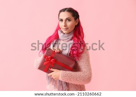 Beautiful woman with Christmas gift box on pink background