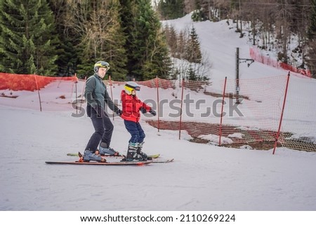 Boy learning to ski, training and listening to his ski instructor on the slope in winter