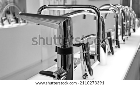 Various kitchen faucets in a row. Reduce your water consumption using a smart faucet. Touchless or manual operation. Black and white photo
