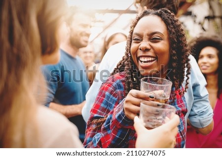 two girls of different races toast together at the college end-of-year party - biracial friends who get together having fun on the dance floor on the terrace drinking and dancing together. Royalty-Free Stock Photo #2110274075