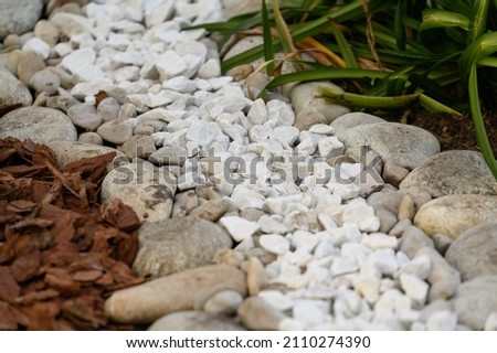 the use of natural materials in landscape design. Pine bark, white stones and pebbles as decoration of the green area in the city. Royalty-Free Stock Photo #2110274390