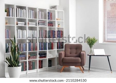 Bookcase with armchair in modern interior of room Royalty-Free Stock Photo #2110284530