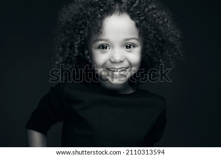 The natural beauty of a little girl under the effect of black and white and also the splendor of her color under the light of a studio decorated by her charm and her smile.