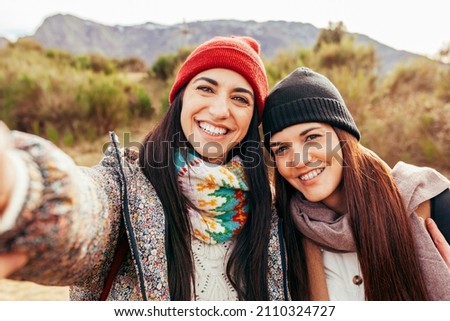 Two young beautiful hiker women taking selfie portrait on the top of mountain - Happy smiling sisters enjoying together - Hiking and climbing cliff