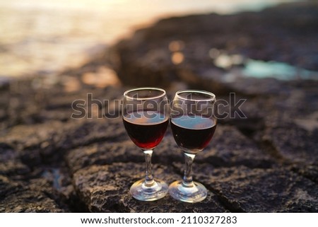 Close up on hands holding red wine glasses on the beach during sunset in Croatia, celebration concept Romantic evening. Vacation concept