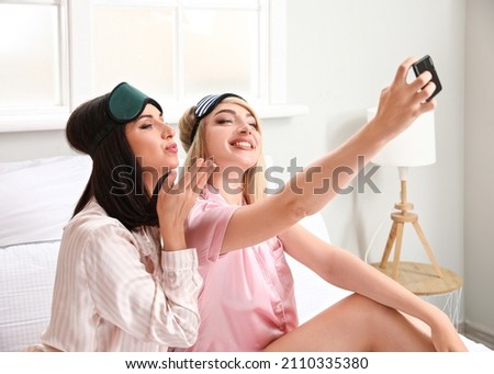 Beautiful young women taking selfie in bedroom