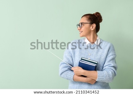 Portrait of female teacher with books and pointer on color background