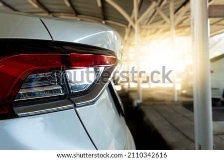 Beside tail lights of white car in parking area. Parked in a covered garage with blurred of other cars. Royalty-Free Stock Photo #2110342616