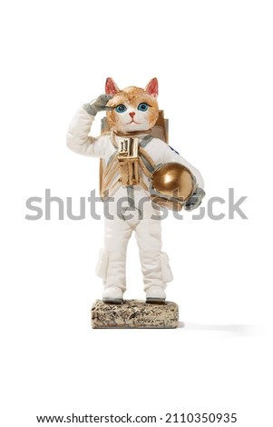 Detail shot of a figurine of a red astronaut cat in a white spacesuit with a helmet off. The cat salutes with the right hand. The statuette is isolated on the white background.