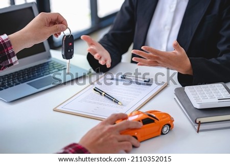 Insurance officers hand over the car keys after the tenant. have signed an auto insurance document or a lease or agreement document Buying or selling a new or used car with a car Royalty-Free Stock Photo #2110352015