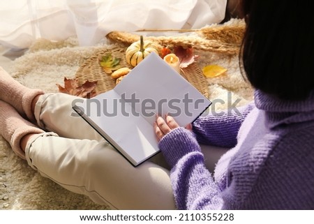 Woman holding book with blank pages in room