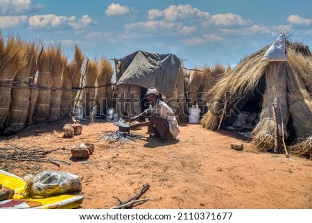 old man in an African village with shacks with thatched roof