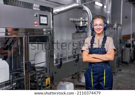 Female worker in protective uniform working in medical supplies research and pesticides production factory, woman is controlling production of bottles canisters before shipment. Industrial warehouse. Royalty-Free Stock Photo #2110374479