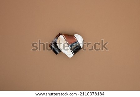 Slide negative film and wooden heart shape on pastel background. Lovo or Photo concept. Flat lay.