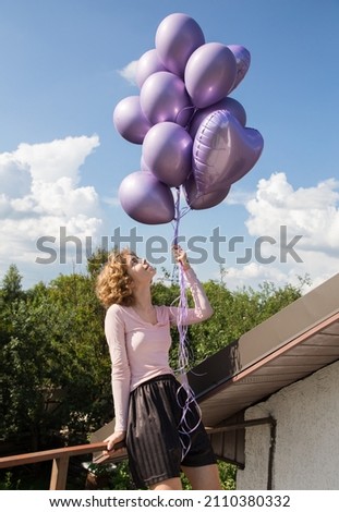 young happy pretty girl 17-18 years old with a bunch of purple helium balloons. Birthday girl. Happy day. The concept of joy, freedom, positivity and congratulations. Dreams, festive mood