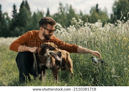 Caucasian man and two dogs in tall grass in rural. Royalty-Free Stock Photo #2110381718