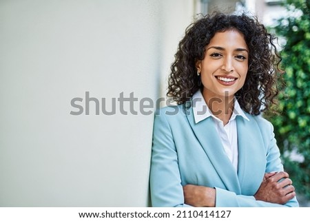 Young hispanic business woman wearing professional look smiling confident at the city leaning on the wall Royalty-Free Stock Photo #2110414127