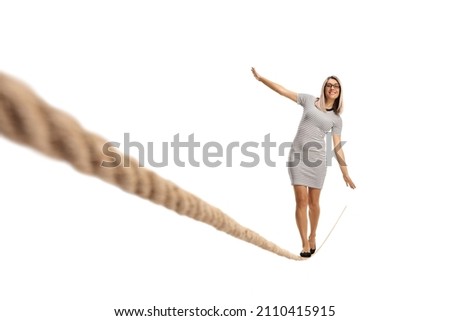 Full length portrait of a young woman walking on a thightrope isolated on white background