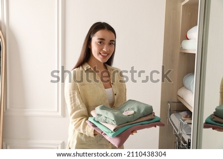 Beautiful woman with clothes and scented sachet near wardrobe Royalty-Free Stock Photo #2110438304