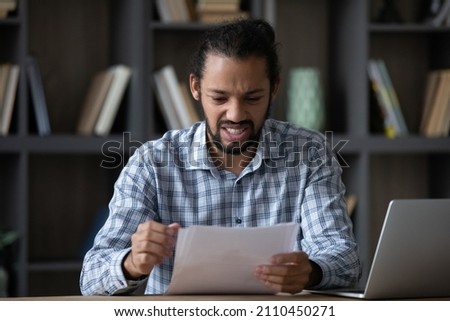 Frustrated worried Afro American employee man reading document with bad dismissal news. Disappointed angry student guy receiving paper letter, rejection notice from business college, feeling stress