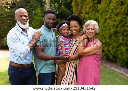 Portrait of smiling three generational african american family standing together at garden. family, love and togetherness concept, unaltered. Royalty-Free Stock Photo #2110451642