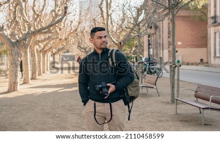 photographer smiling in the middle of a park while holding a cam