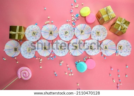 Text Happy Birthday by wooden letters with birthday asseccories on pink background top view in cupcake case space for text