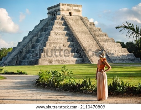 Girl tourist in a hat stands against the background of the pyramid of Kukulcan in the Mexican city of Chichen Itza. Travel concept.Mayan pyramids in Yucatan, Mexico Royalty-Free Stock Photo #2110470809