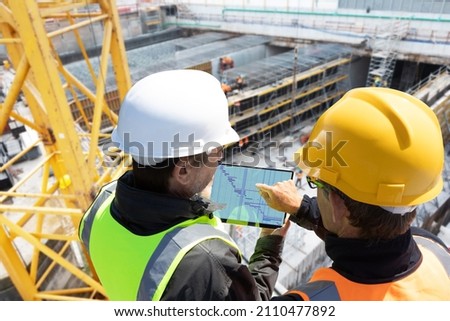 two people architect engineer worker on major constructionsite checking progress report on computer laptop tablet together as team  Royalty-Free Stock Photo #2110477892