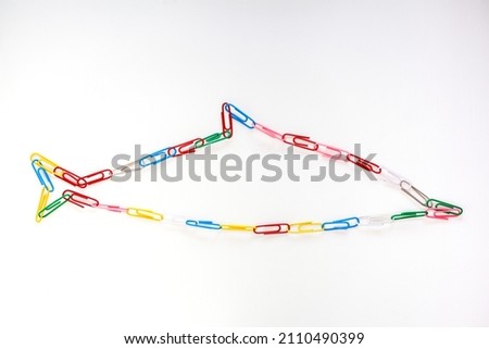 The figure of a dolphin from colored school paper clips on a white background Royalty-Free Stock Photo #2110490399