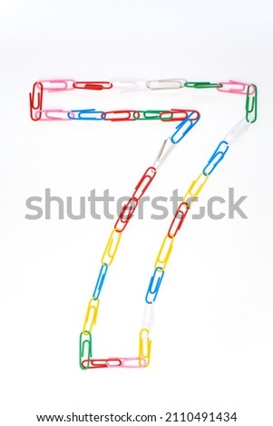 Figure number seven from colored school paper clips on a white background Royalty-Free Stock Photo #2110491434