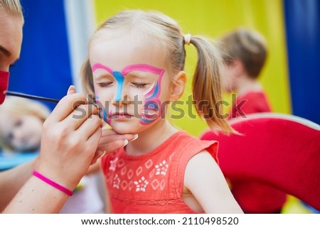 Children face painting. Artist painting little preschooler girl like butterfly. Creative activities for kids Royalty-Free Stock Photo #2110498520